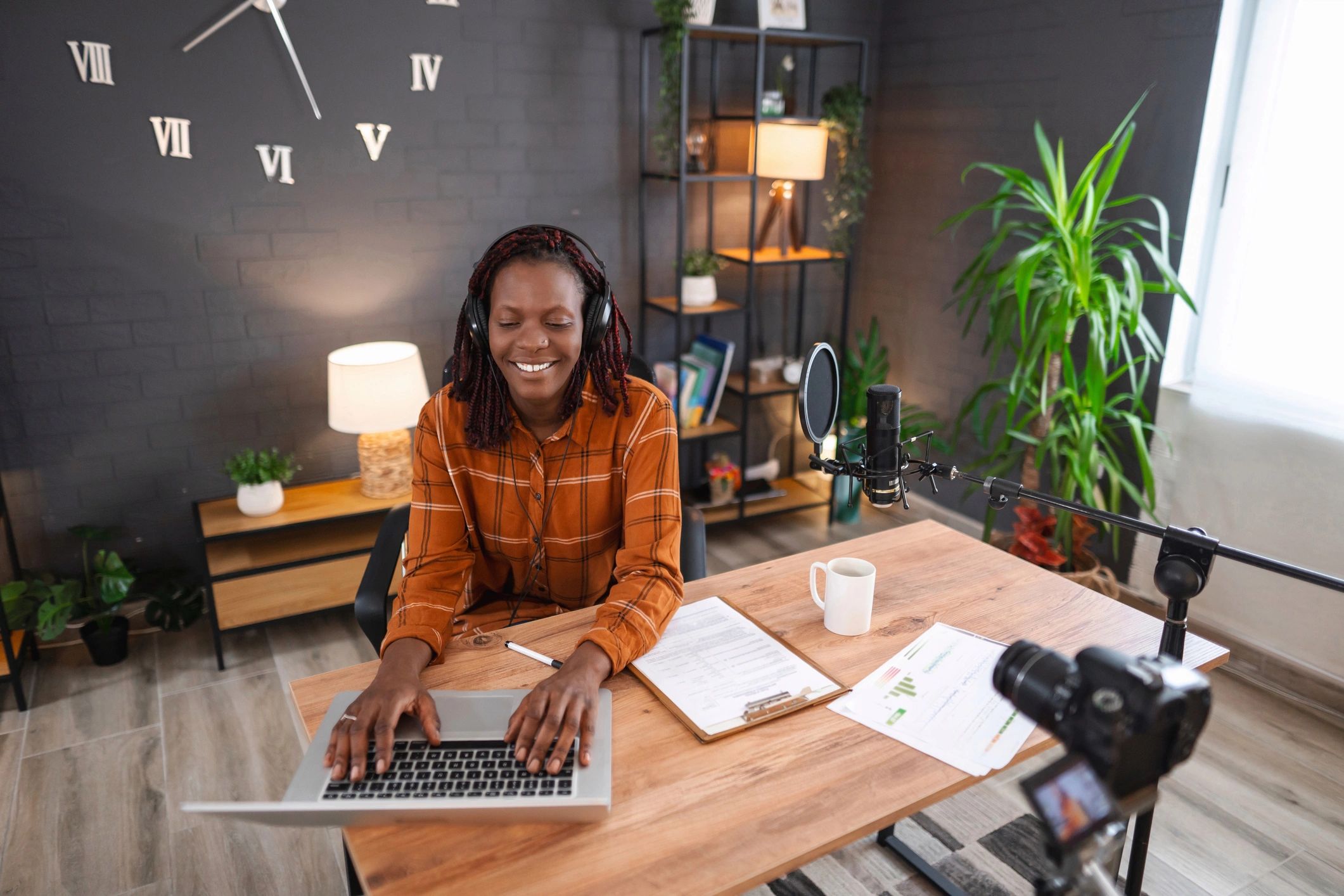 Woman recording a podcast in a home studio with microphone and laptop.